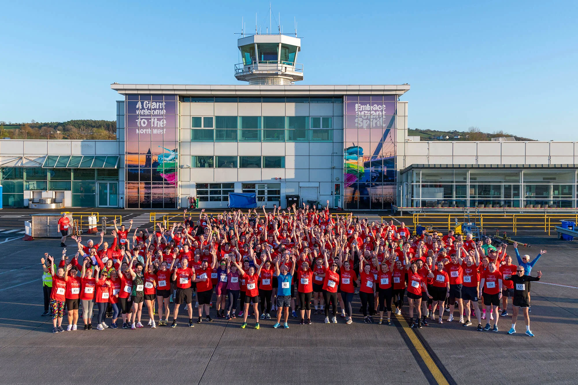 Runners of the Air Ambulance NI City of Derry Airport run posing for a photo infront of the Airport